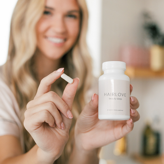 Smiling woman holds a capsule and a bottle labeled HAIRLOVE beauty sleep 30 capsules / dietary supplement.