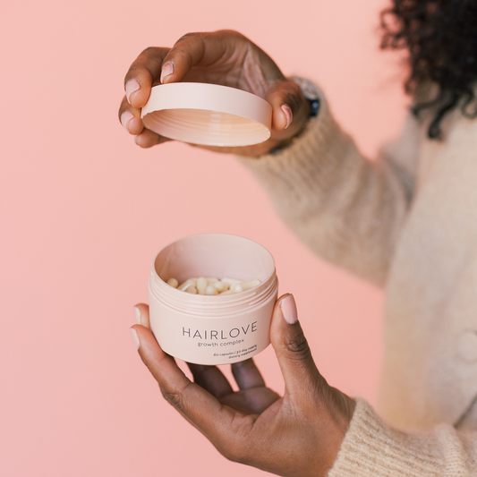 Hands lifting the lid of a jar of pills labeled HAIRLOVE growth complex — 60 capsules | 30 day supply dietary supplement