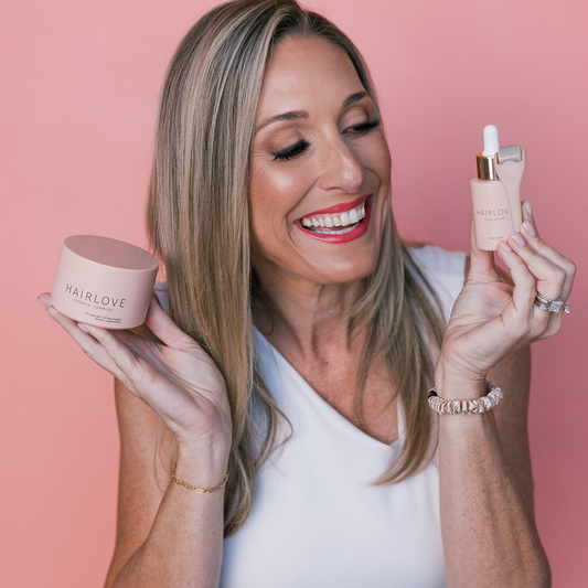 Woman smiling, holding two HAIRLOVE items: jar 'HAIRLOVE GROWTH COMPLEX' and dropper 'HAIRLOVE scalp serum 1 fl oz (30 ml)'