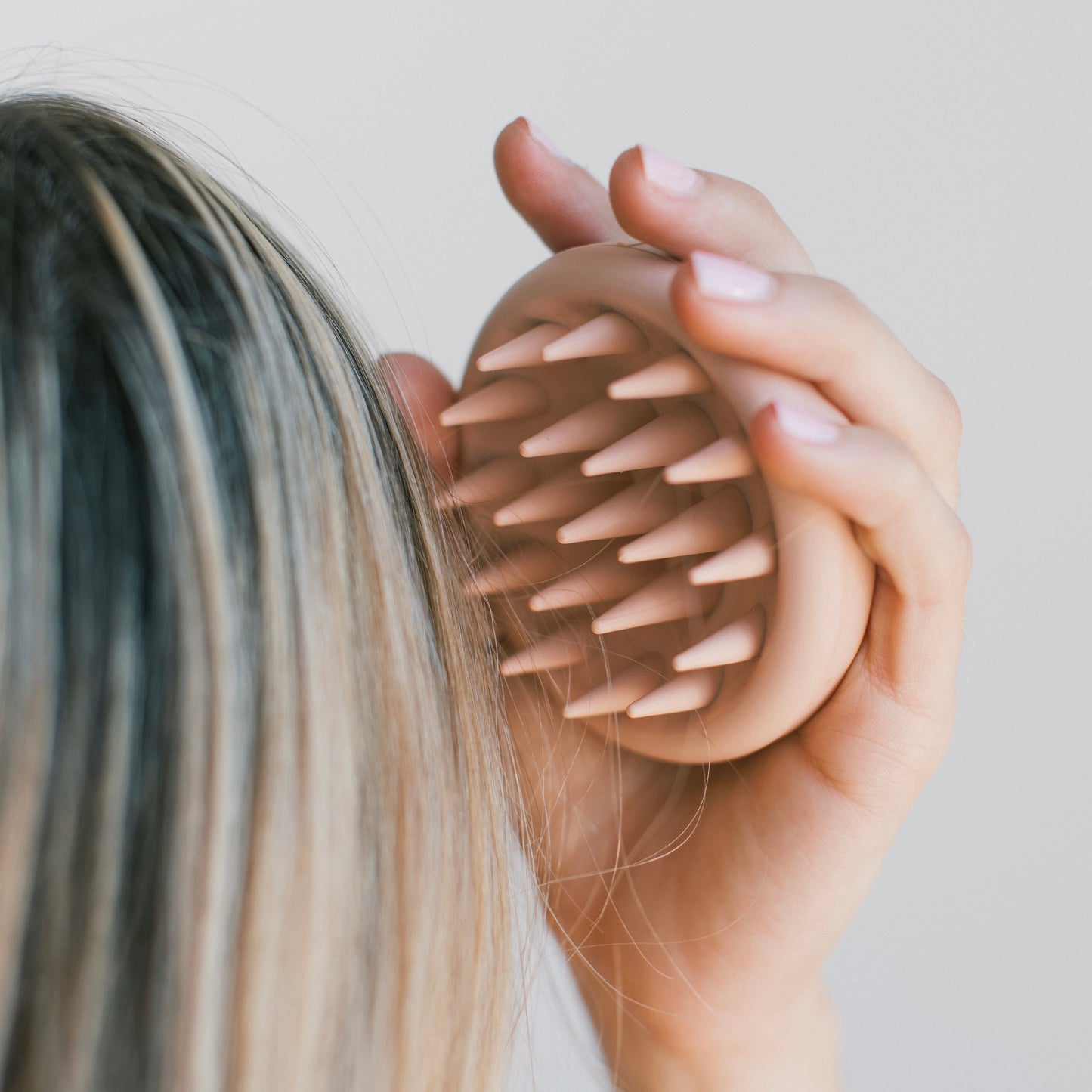 Close-up of a hand holding a detox scalp massager against hair