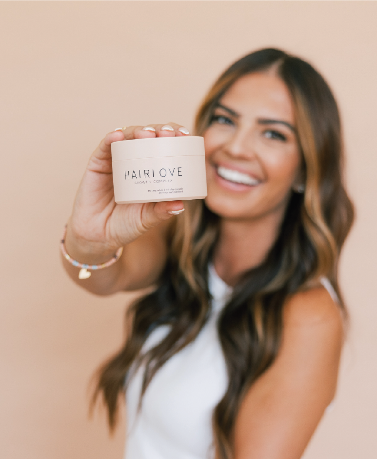 A person smiling and holding a HAIRLOVE Growth Complex product.