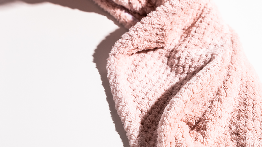 Close-up of pink microfiber hair towel highlighting plush texture and waffle weave with soft shadow on white background