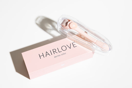 Three-quarter view of pink derma roller in clear case with HAIRLOVE box showing brand name on white background