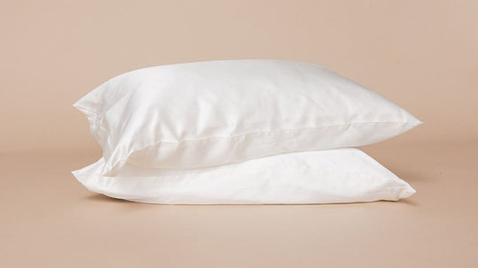 Two stacked white pillows on a beige background suggesting sleep and rest