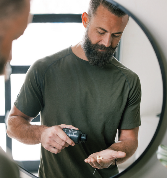 Man with a beard holding a Black bottle of HAIRLOVE hair growth complex for men, daily hair vitamin 