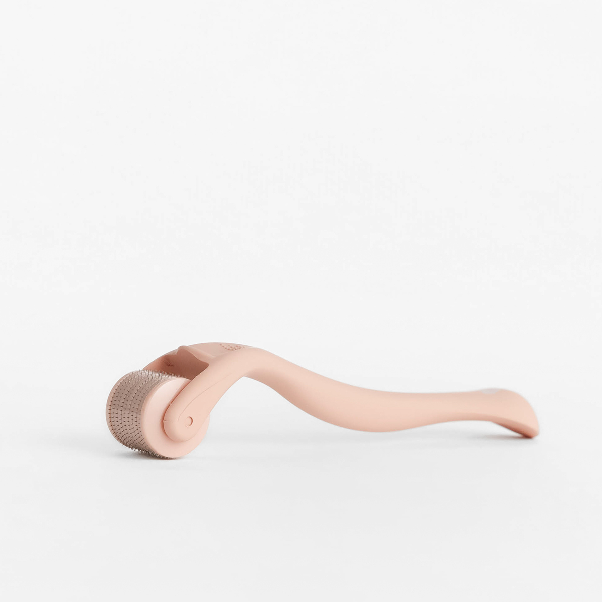 Side view of Derma Roller showing microneedle roller head and curved pink handle on white background