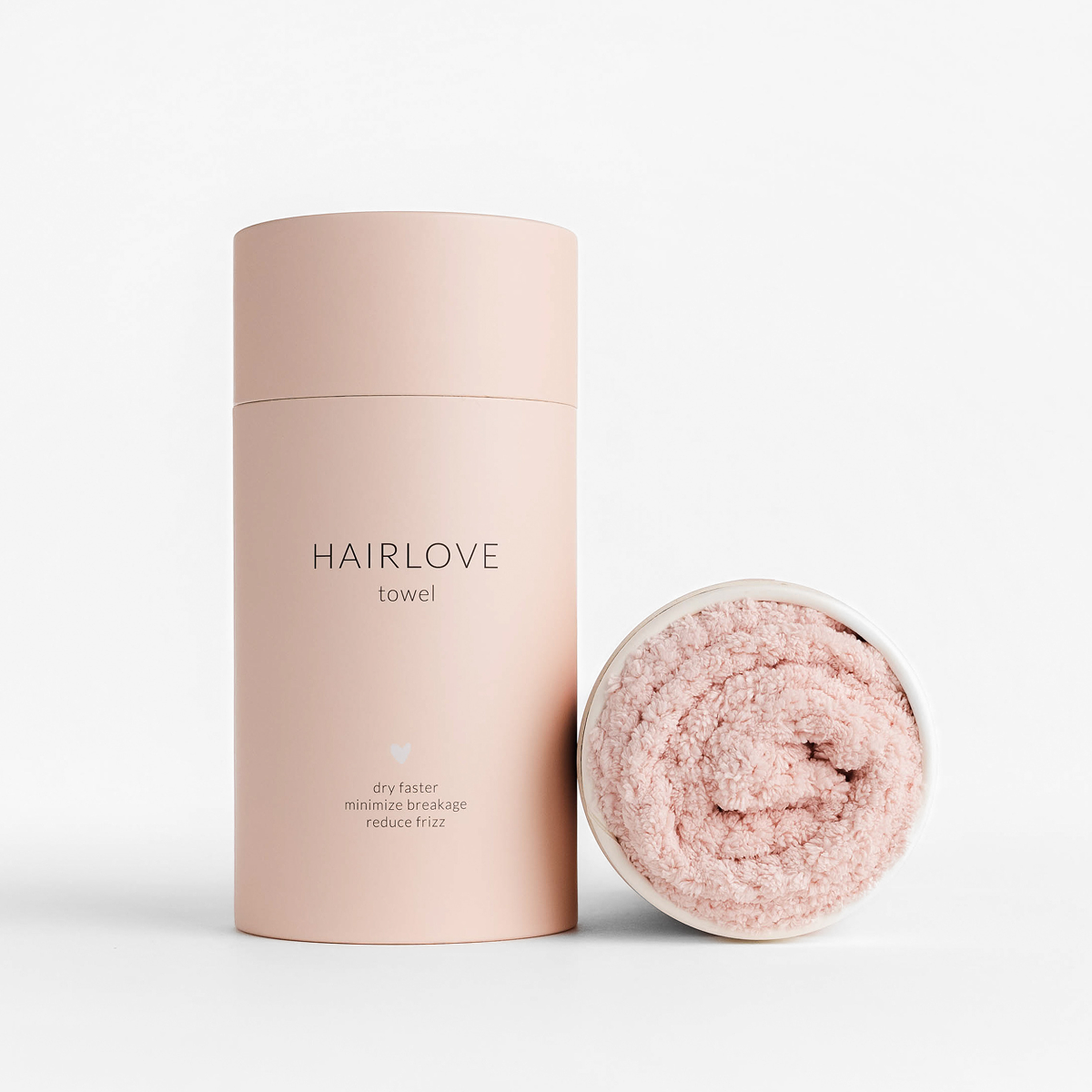 Front view of Luxury Hair Towel showing blush-pink rolled microfiber towel and cylindrical branded tube on white background