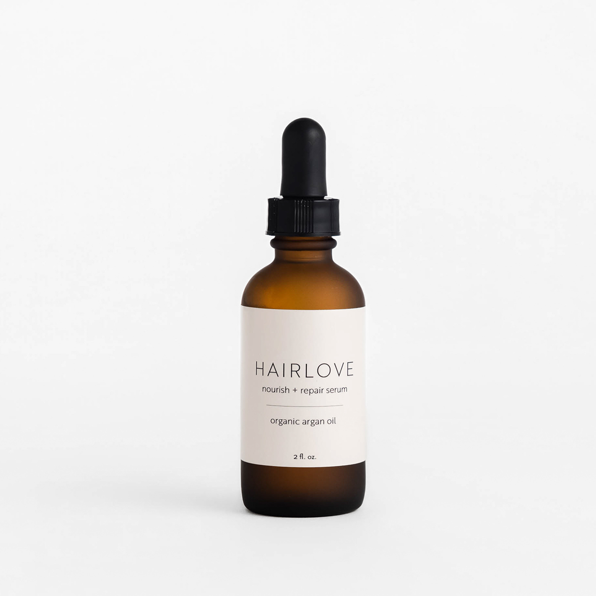 Front view of Nourish + Repair serum bottle showcasing amber glass dropper and Hairlove label on white background